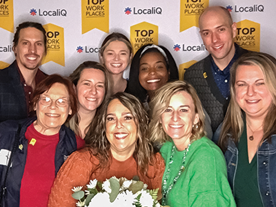 AAA Life team members group photo in front of top work places awards banner